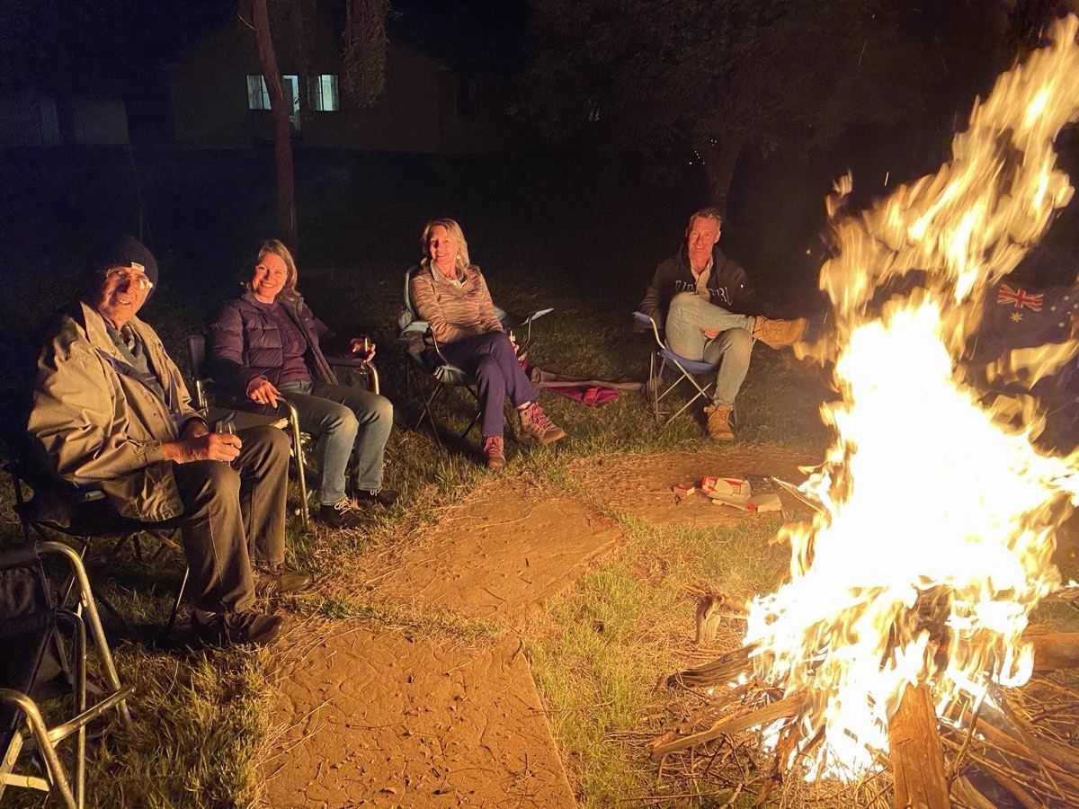 Friends sitting around a large campfire at night